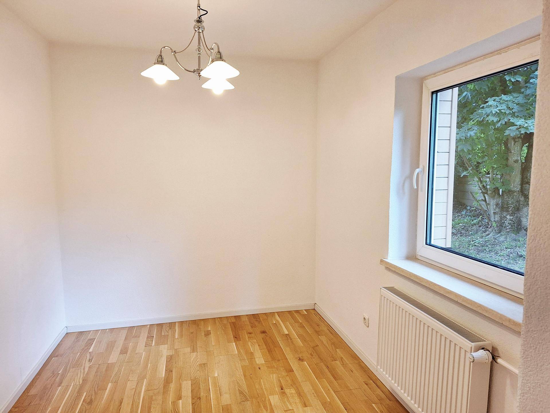 Leerer Essbereich mit Parkettboden, Fenster und Heizkörper, bereit zur individuellen Gestaltung.