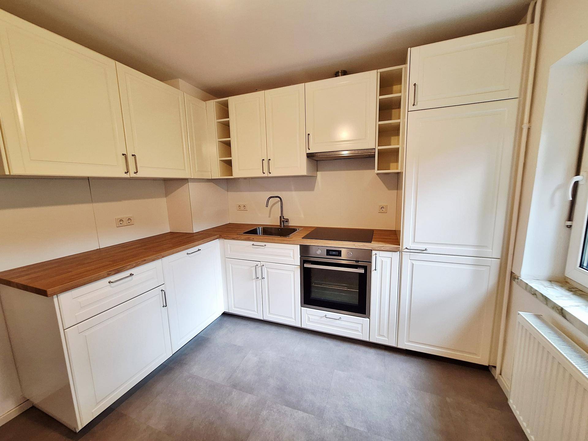Moderne Einbauküche in Weiß mit Holz-Arbeitsplatten und integrierten Geräten.