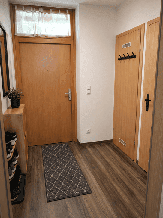 Heller Eingangsbereich mit Garderobe und Schuhregal, bietet praktischen Stauraum.