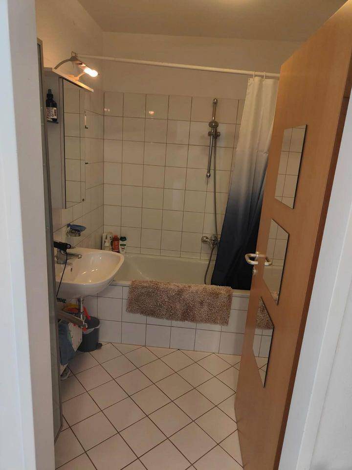 Badezimmer mit Badewanne, Duschvorhang, Waschbecken und weißen Fliesen.