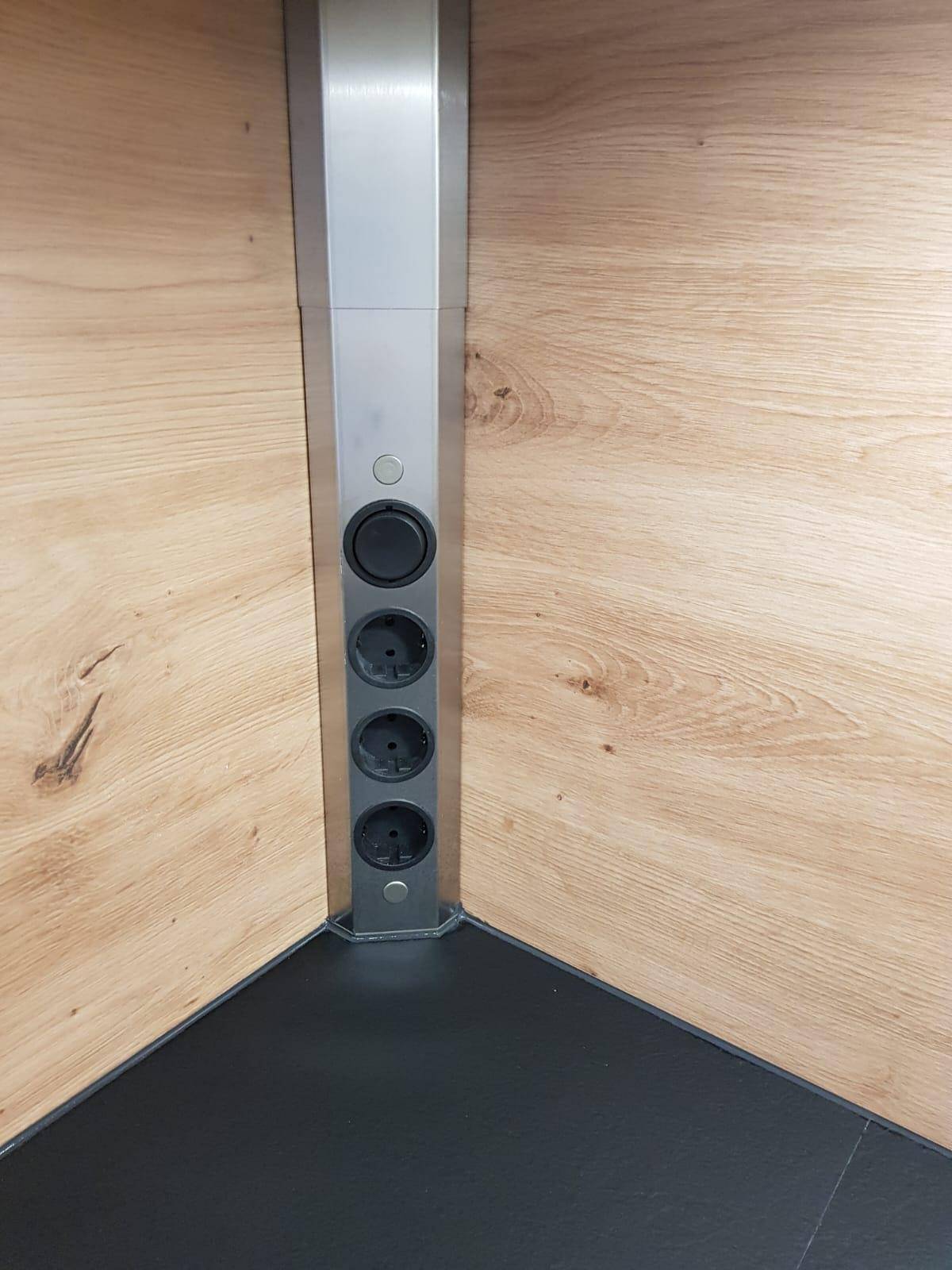 Detailansicht einer modernen Steckdosenleiste in der Küche mit Holzrückwand.