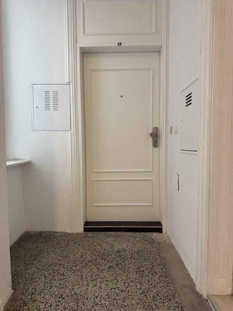 Eingangsbereich einer Wohnung mit weißer Tür und Terrazzoboden.