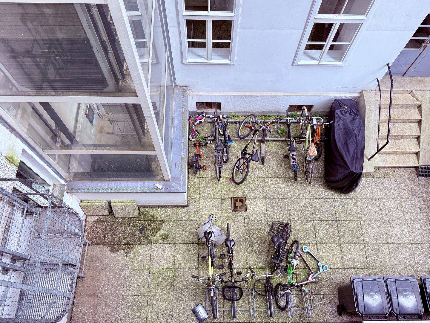 Fahrradabstellplatz im Innenhof eines Gebäudes mit gepflastertem Boden.
