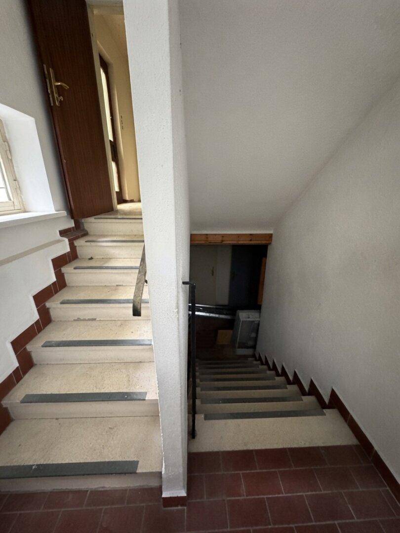 Treppenhaus mit gefliesten Stufen und Geländer, das in die oberen Stockwerke führt.