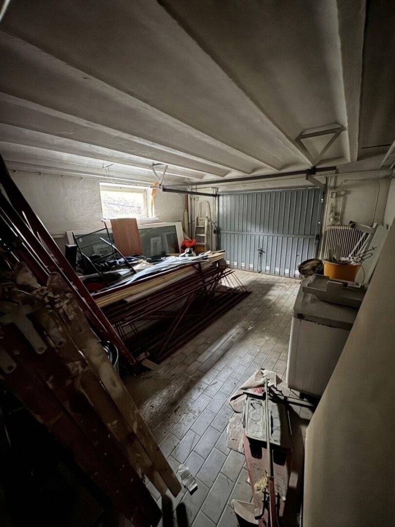 Geräumige Garage mit Betonboden und Lagerflächen, bereit für verschiedene Nutzungsmöglichkeiten.