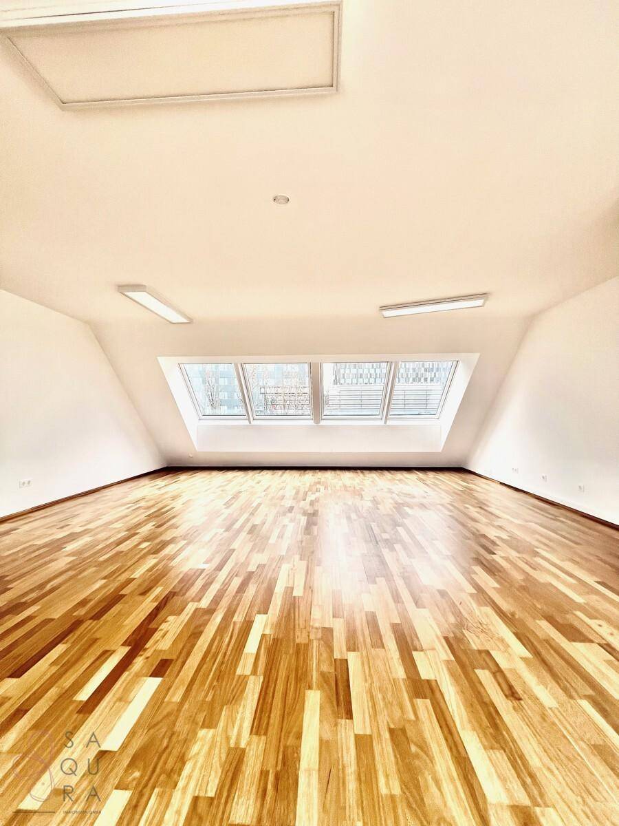 Heller Raum mit Holzboden und großen Dachfenstern, ideal für vielfältige Nutzung.