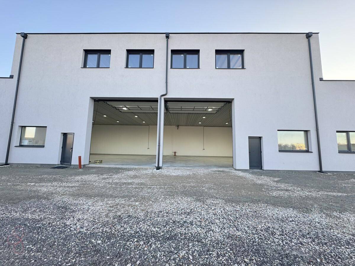 Vorderansicht von zwei modernen Industriegebäuden mit Rolltoren und Fenstern im Obergeschoss.