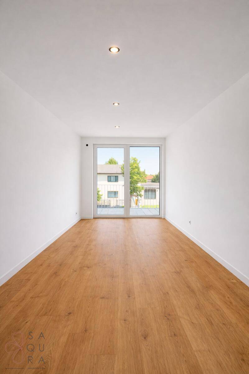 Heller, leerer Raum mit großen Fenstern und Blick ins Grüne, ideal für Wohn- oder Schlafzimmer.