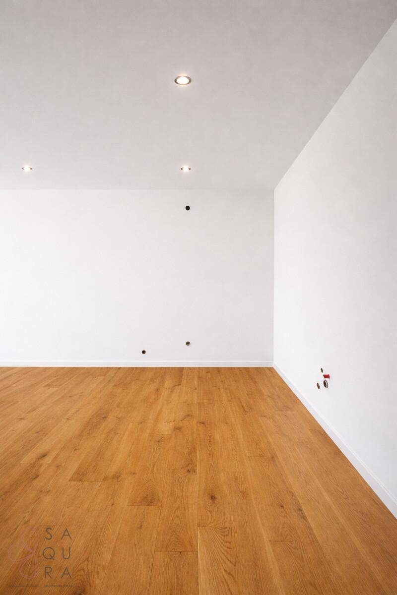 Ecke eines hellen Raumes mit Parkettboden und weißen Wänden, ausgestattet mit modernen Steckdosen.