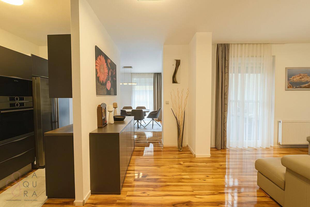 Offener Wohnbereich mit Holzboden, der in den Essbereich und die Küche übergeht.