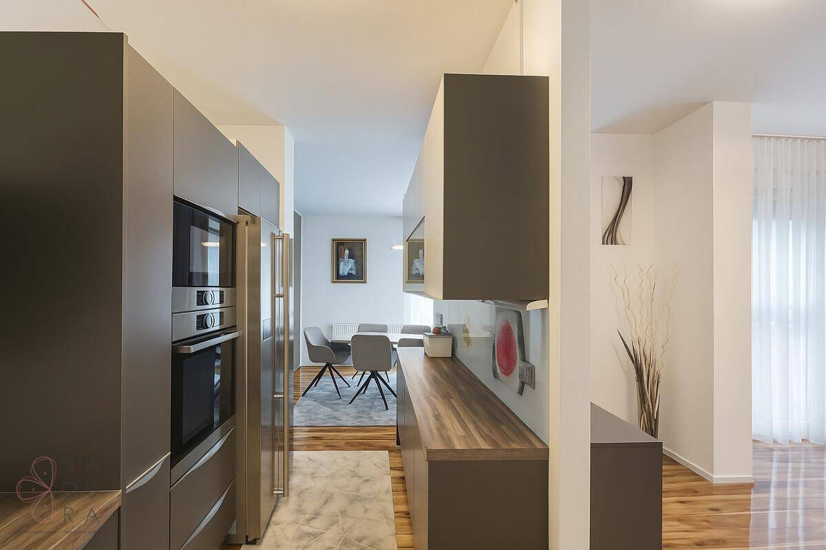 Moderne Küche mit dunklen Schränken, integrierten Geräten und Blick auf den Essbereich.