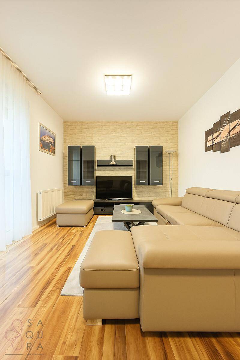 Helles Wohnzimmer mit beiger Ledercouch, Holzboden und stilvoller Wanddekoration.