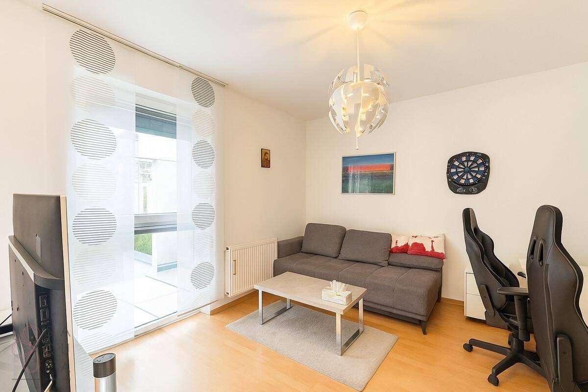 Helles Zimmer mit Sofa, Schreibtisch und großem Fenster, ideal als Arbeits- oder Gästezimmer.