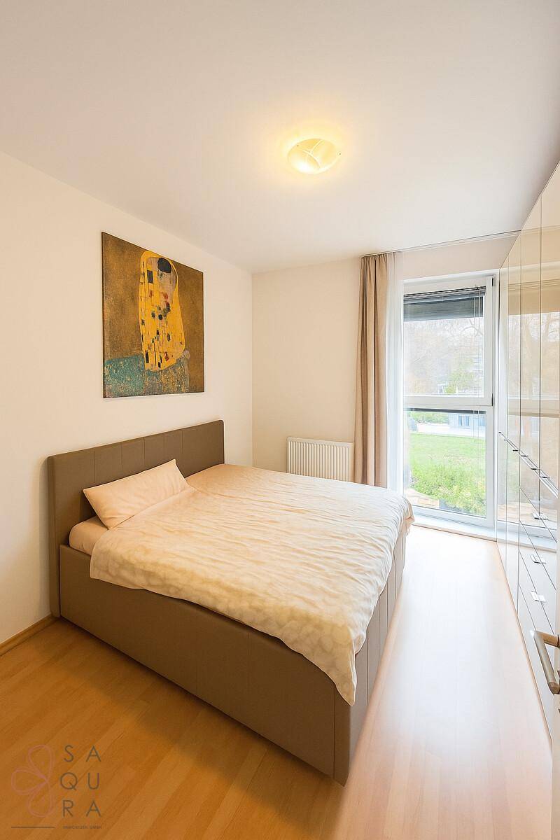 Gemütliches Schlafzimmer mit Doppelbett, Holzboden und großem Fenster mit Blick ins Grüne.