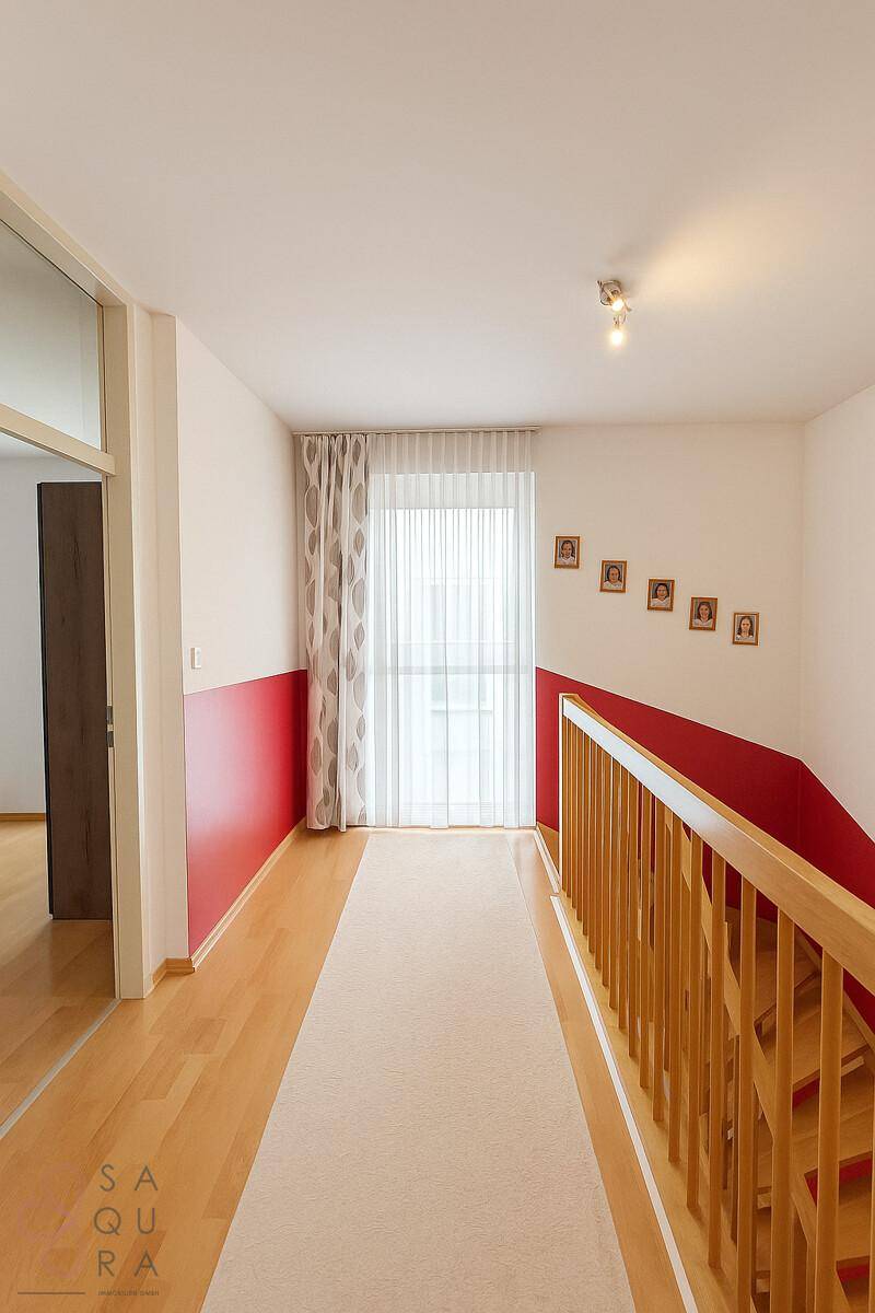 Heller Flur im Obergeschoss mit Holzboden, Teppichläufer und Zugang zu weiteren Räumen.