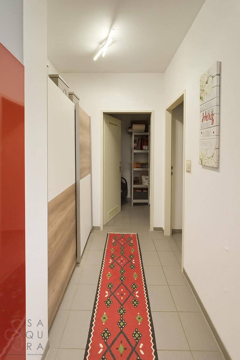 Heller Flur mit Fliesenboden, integrierten Schränken und Zugang zu einem Abstellraum.
