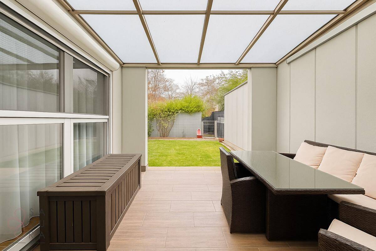 Geräumige überdachte Terrasse mit Gartenblick und Zugang zum Rasenbereich.