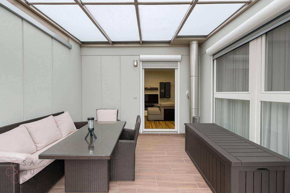 Überdachte Terrasse mit Outdoor-Möbeln und Blick in den Garten.