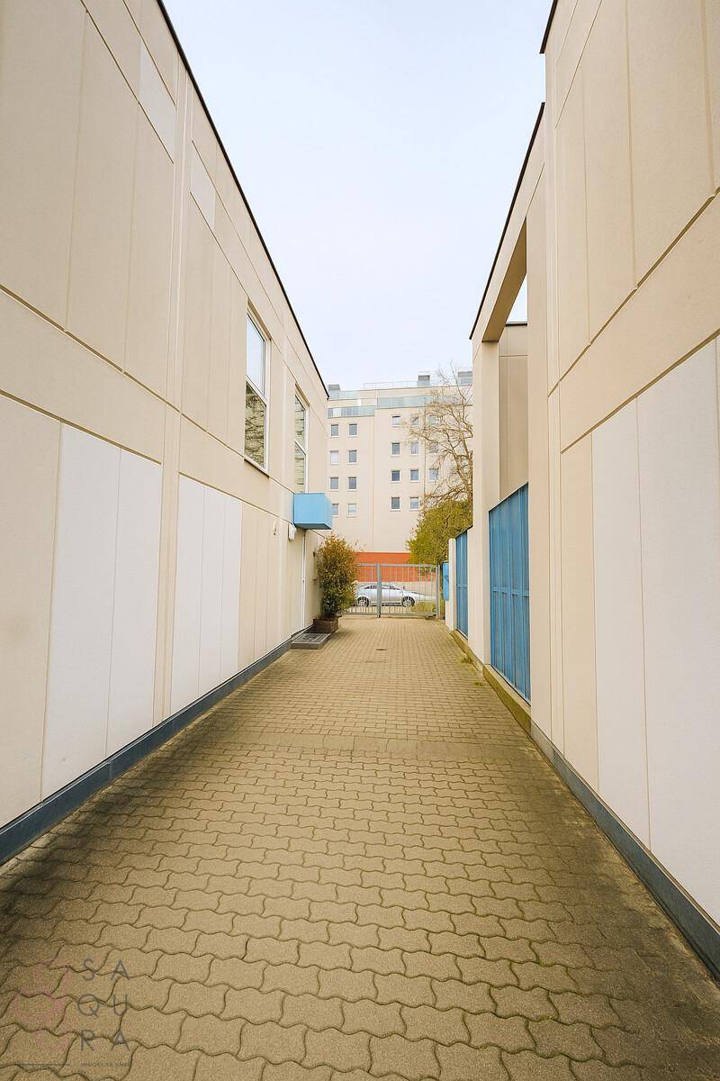 Gepflasterter Zugangsweg zwischen Gebäuden mit Blick auf weitere Wohngebäude.