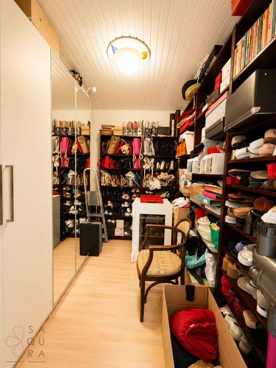 Begehbarer Kleiderschrank mit zahlreichen Regalen für Schuhe und Taschen sowie einem Spiegel.