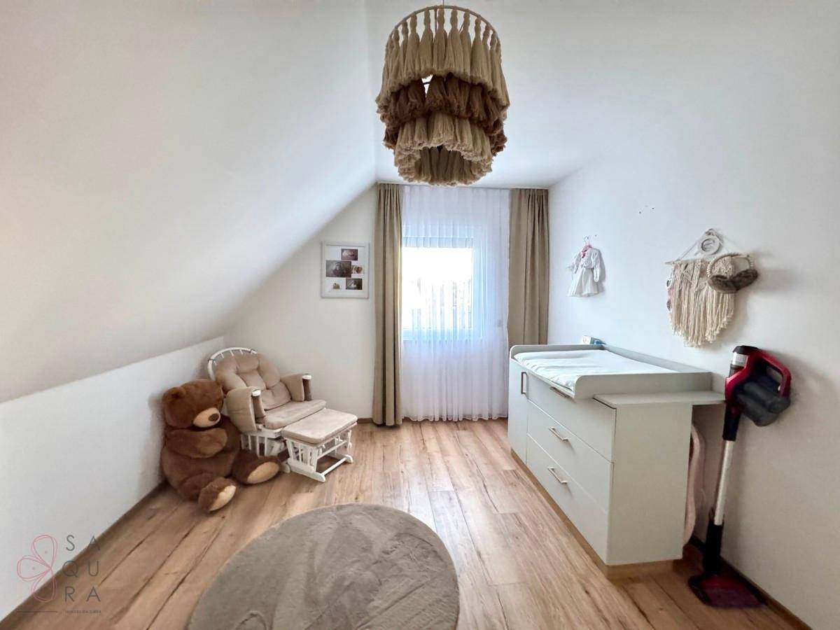 Kinderzimmer im Dachgeschoss mit Wickeltisch, Schaukelstuhl und hellem Holzboden.