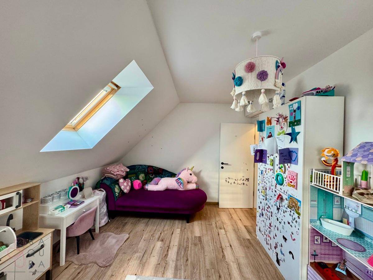 Helles Kinderzimmer im Dachgeschoss mit Dachfenster, Spielzeug und Holzboden.