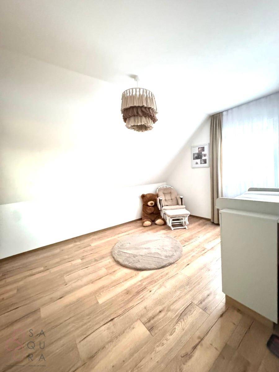 Kinderzimmer im Dachgeschoss mit Holzboden, Schaukelstuhl und Wickeltisch.