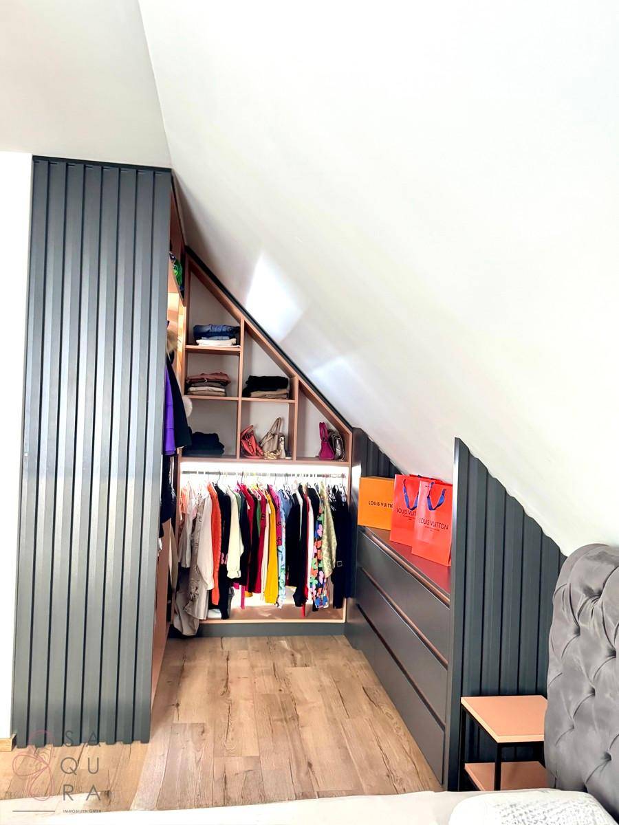 Begehbarer Kleiderschrank im Dachgeschoss mit maßgefertigten Regalen und Kleiderstangen.