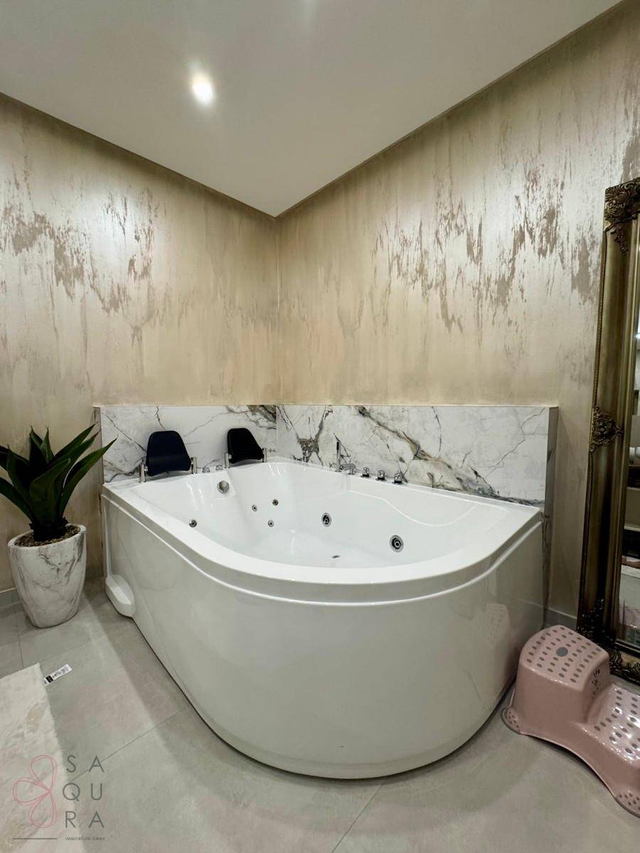 Geräumiges Badezimmer mit eleganter Eck-Whirlpool-Badewanne und dekorativer Wandverkleidung.