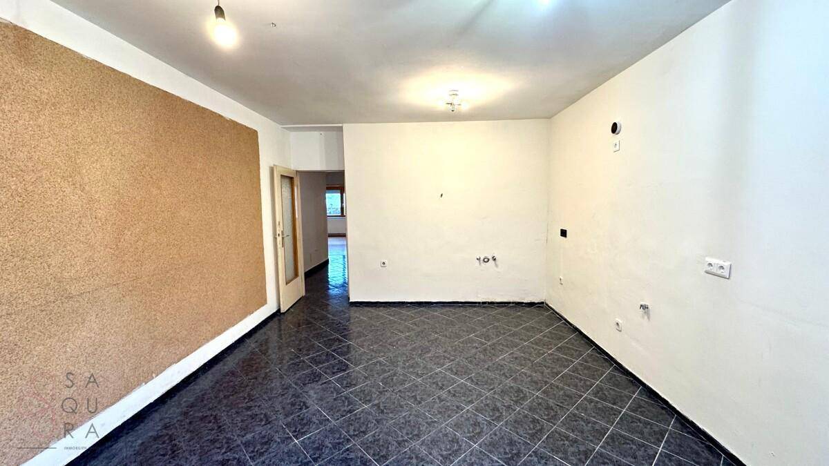 Leerer Küchenbereich mit dunklem Fliesenboden und einer strukturierten Wand, bereit für die Einrichtung.