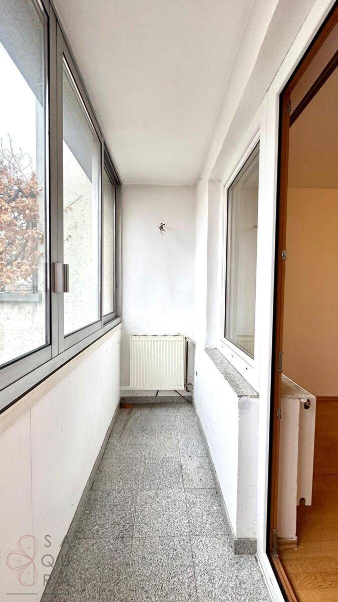 Leerer, verglaster Balkon mit Fliesenboden und Heizkörper, bietet zusätzlichen Wohnraum.