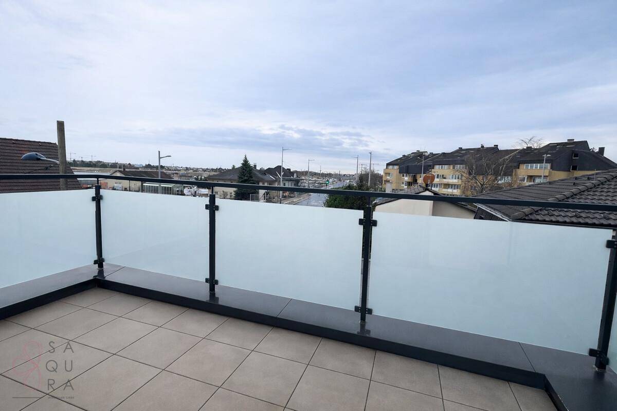Geräumige Terrasse mit Milchglasgeländer und Blick auf die städtische Umgebung.