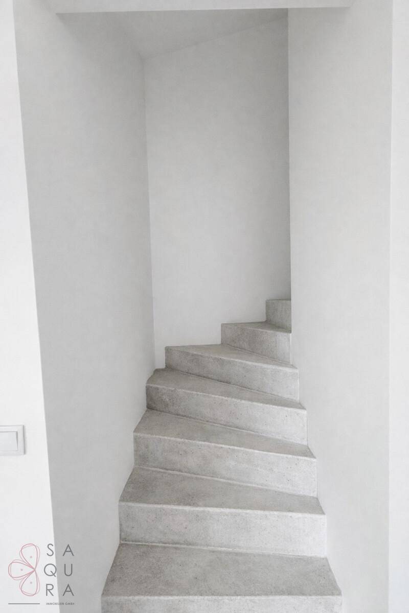Moderne Wendeltreppe aus Beton in einem hellen Treppenhaus.