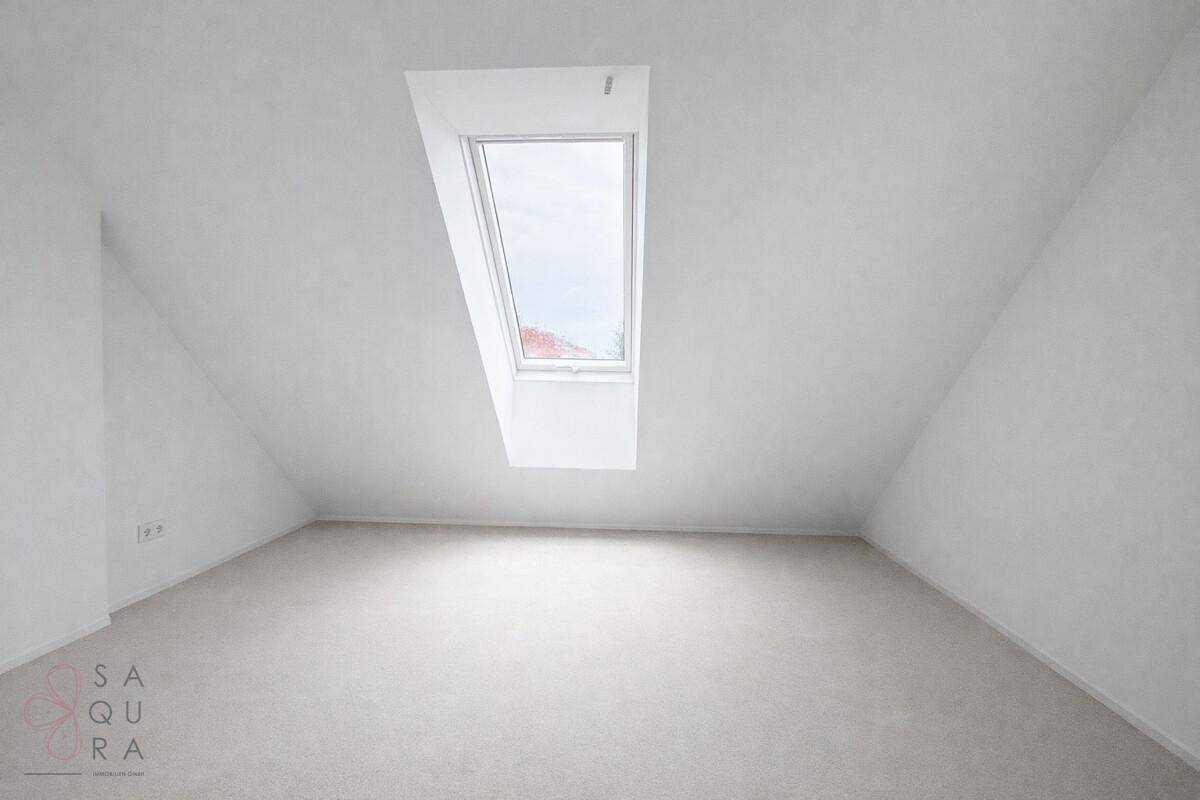 Heller Dachbodenraum mit Dachfenster und schrägen Wänden, ideal für ein weiteres Zimmer.