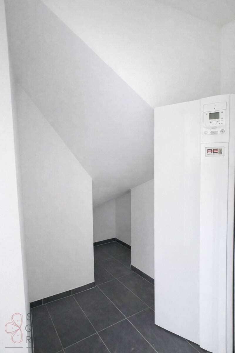 Hauswirtschaftsraum mit Heizungsanlage, dunklen Fliesen und Dachschräge.