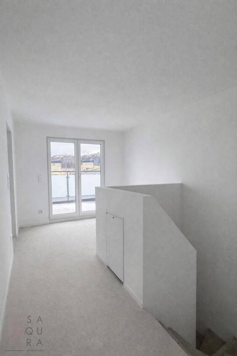 Heller Raum mit Zugang zu einem Außenbereich und einer niedrigen Brüstung.