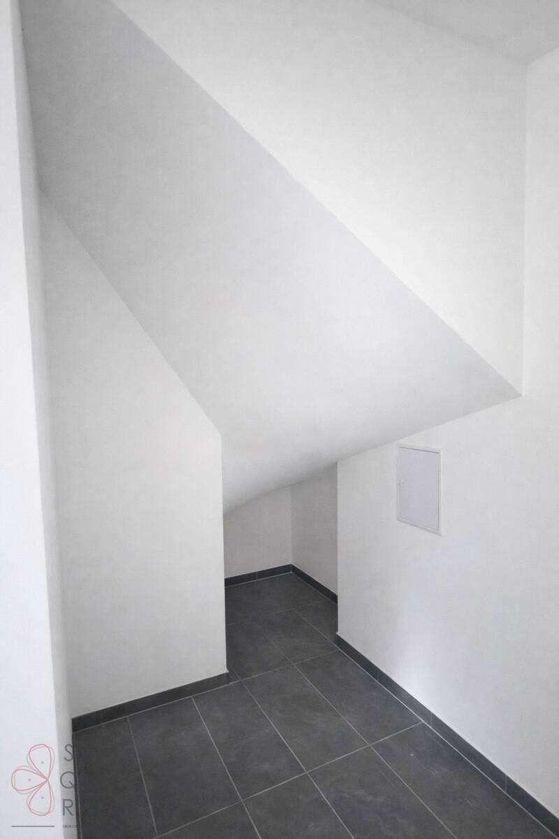 Abstellraum mit dunklem Fliesenboden und charakteristischer Dachschräge.