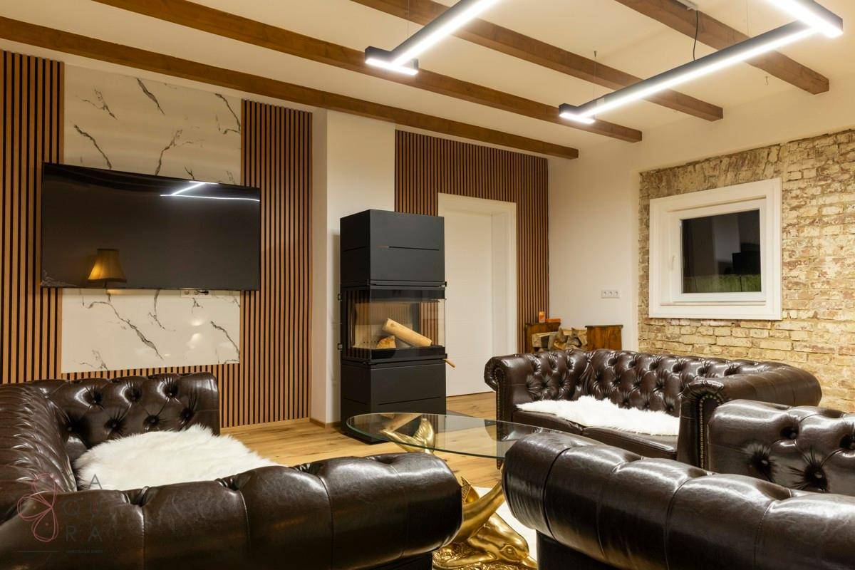 Gemütliches Wohnzimmer mit Kamin, Holzboden und bequemen Ledersofas.