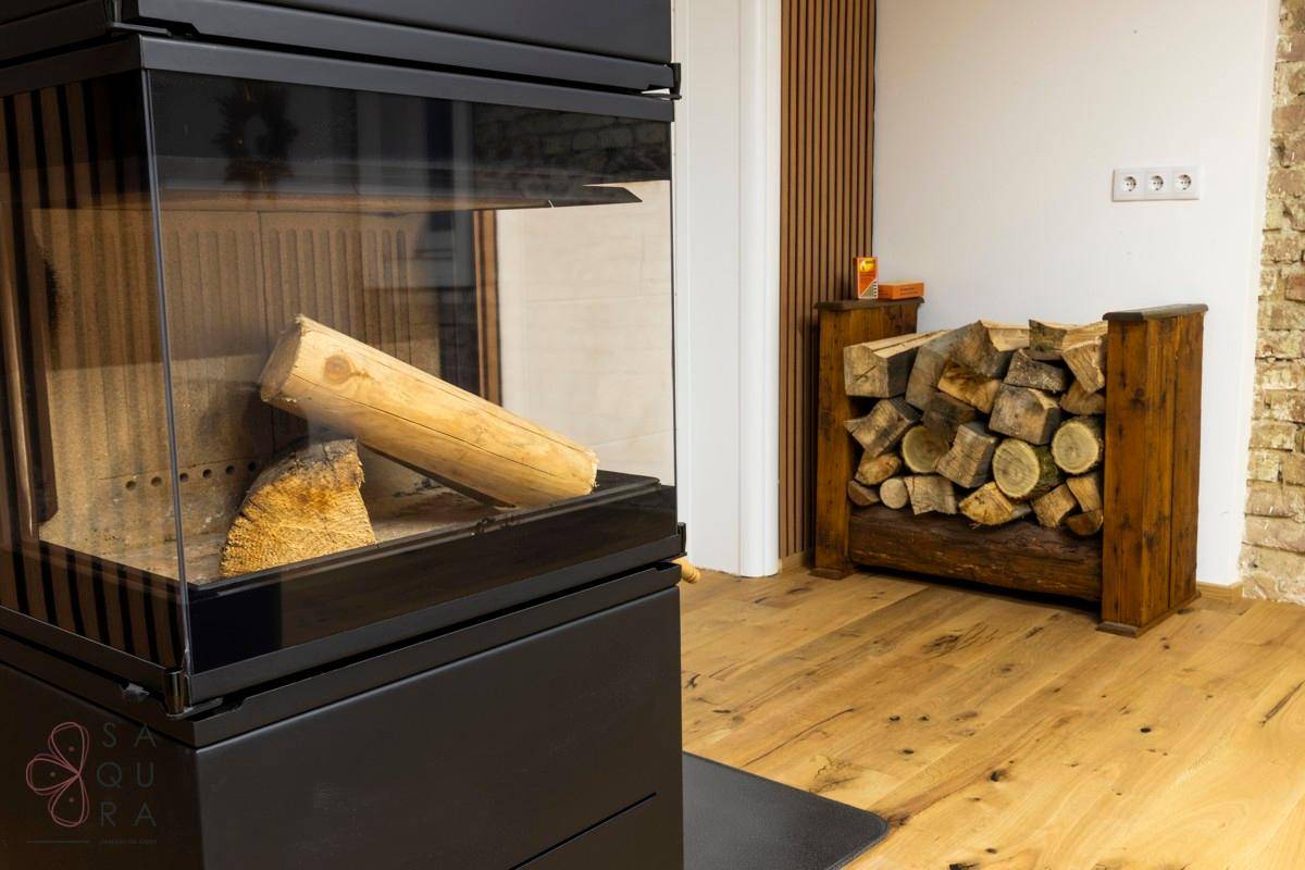 Nahaufnahme des Kamins mit Holzscheiten und einem Holzregal im Hintergrund.