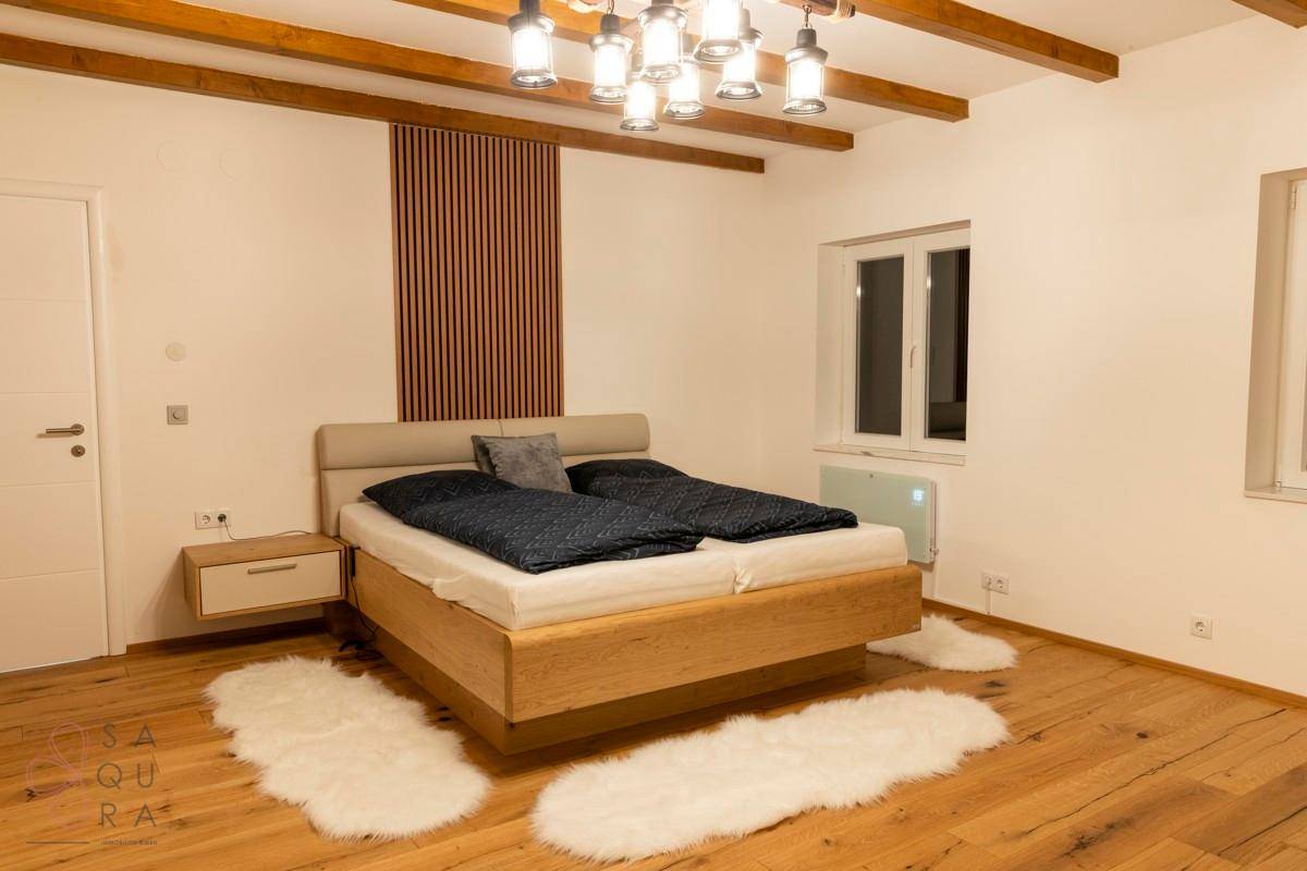 Helles Schlafzimmer mit Holzbalken, Holzboden und einem bequemen Doppelbett.
