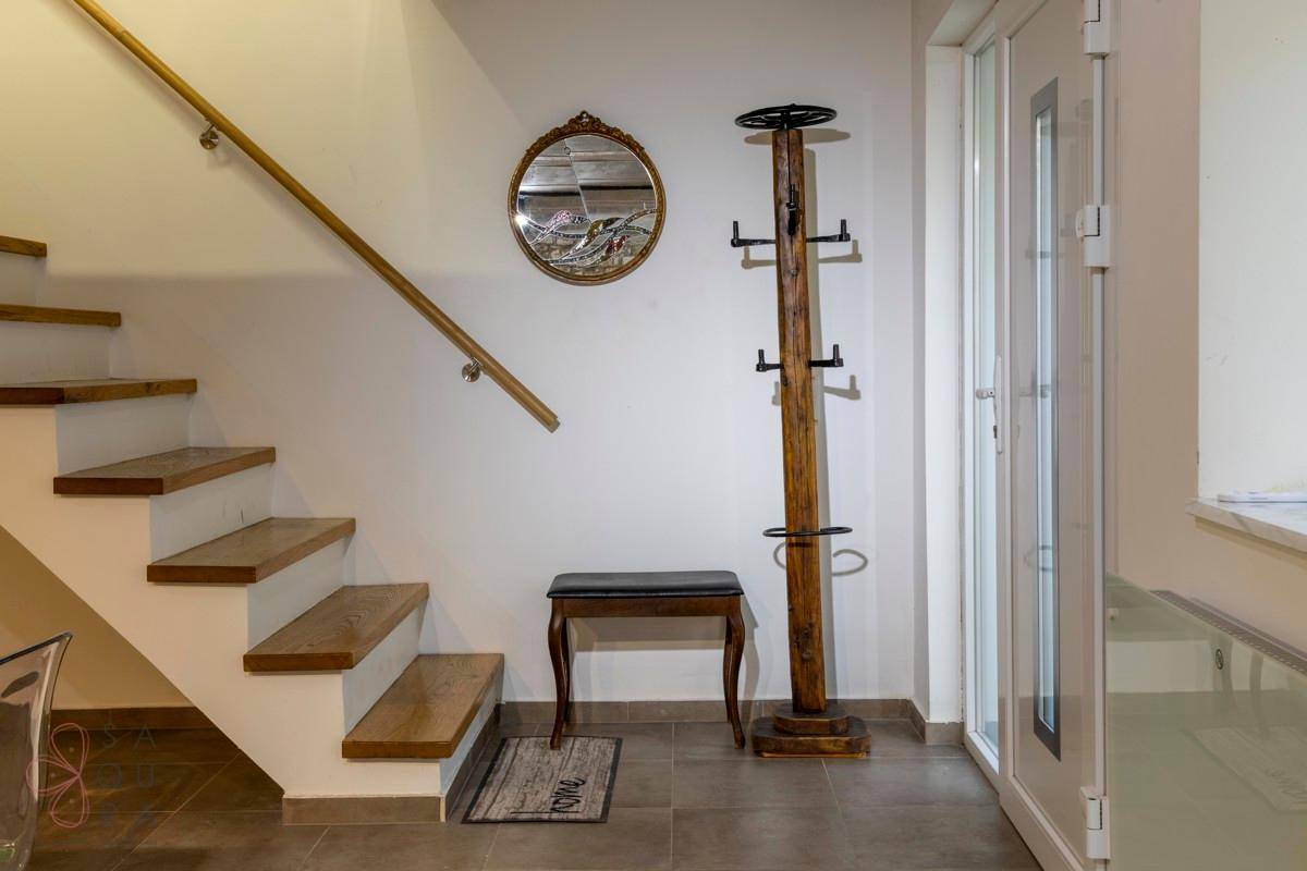 Eingangsbereich mit Holztreppe, Garderobe und Fliesenboden.