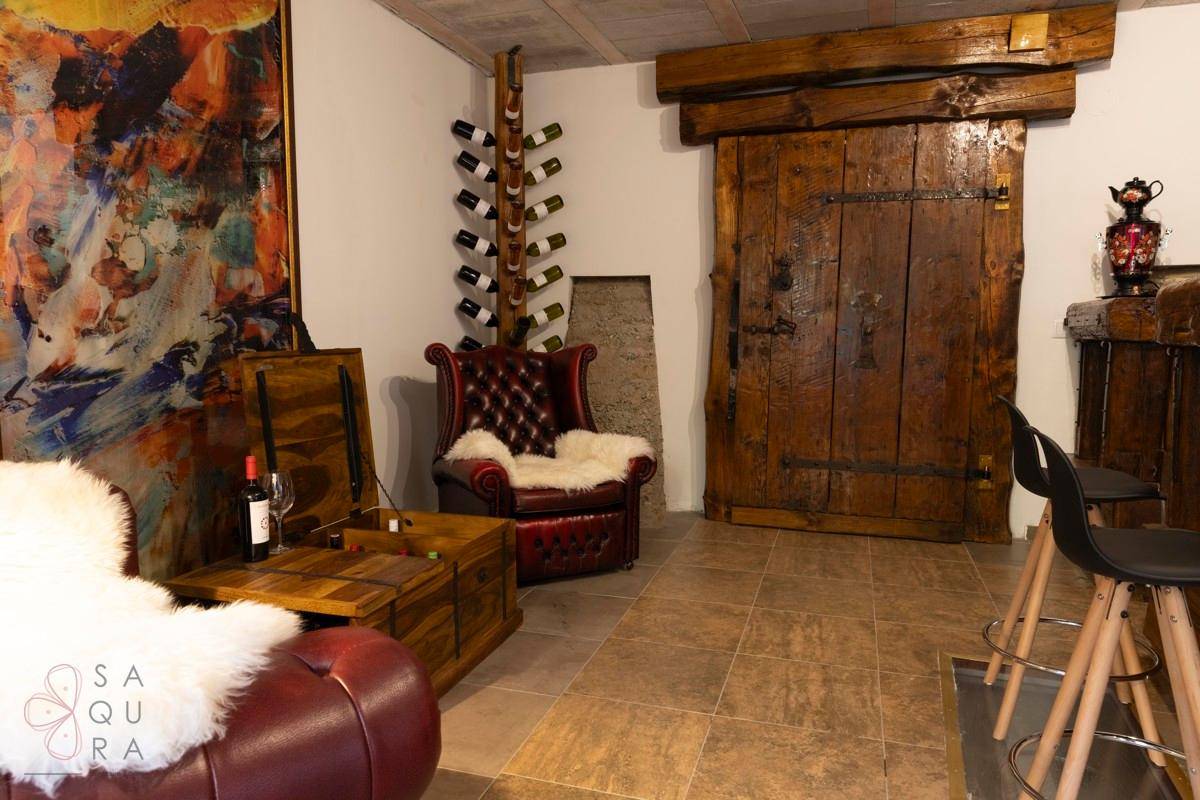 Gemütlicher Kellerraum mit rustikaler Holztür, Weinflaschenregal und Ledersesseln.