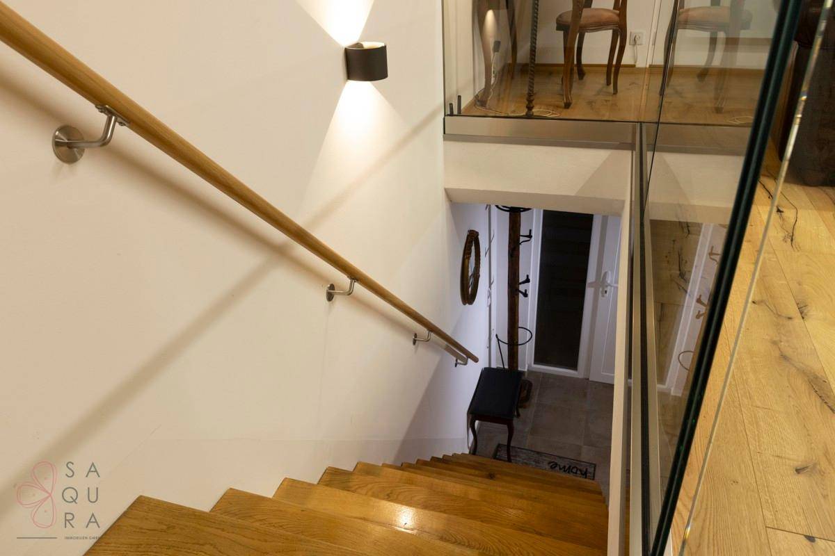 Elegante Holztreppe mit Handlauf und Glasgeländer, die zum unteren Stockwerk führt.