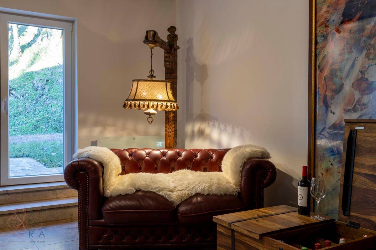Gemütliche Sitzecke im Keller mit Ledersofa, Stehlampe und großem Kunstwerk.