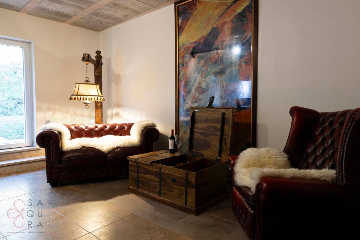 Keller-Lounge mit Ledersofa, Holztruhe und großem Gemälde an der Wand.