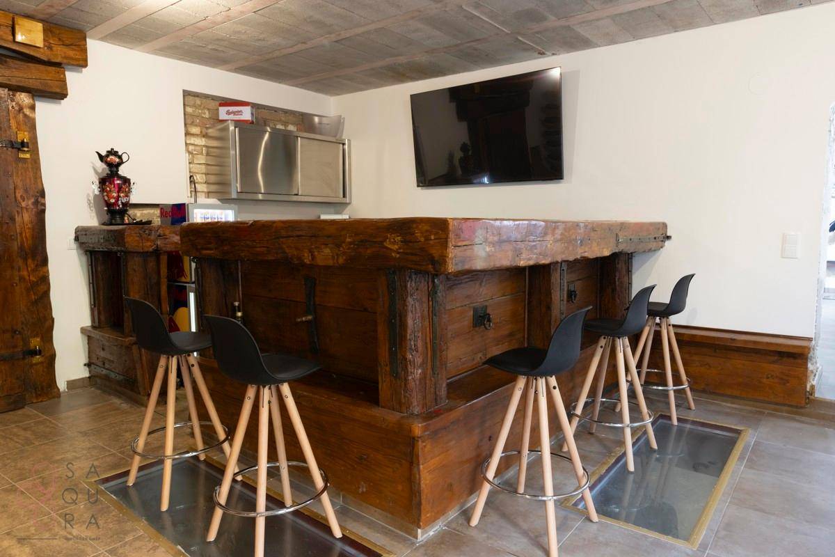 Rustikale Kellerbar mit Holztresen, Barhockern und integriertem Fernseher.