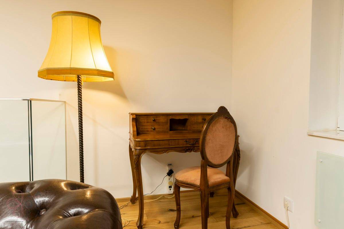 Ein klassischer Holzschreibtisch mit Stuhl und einer großen Stehlampe in einem hellen Raum.