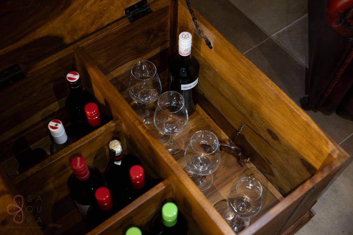 Eine Holzkiste dient als Weinregal mit mehreren Flaschen und Gläsern, offen präsentiert.