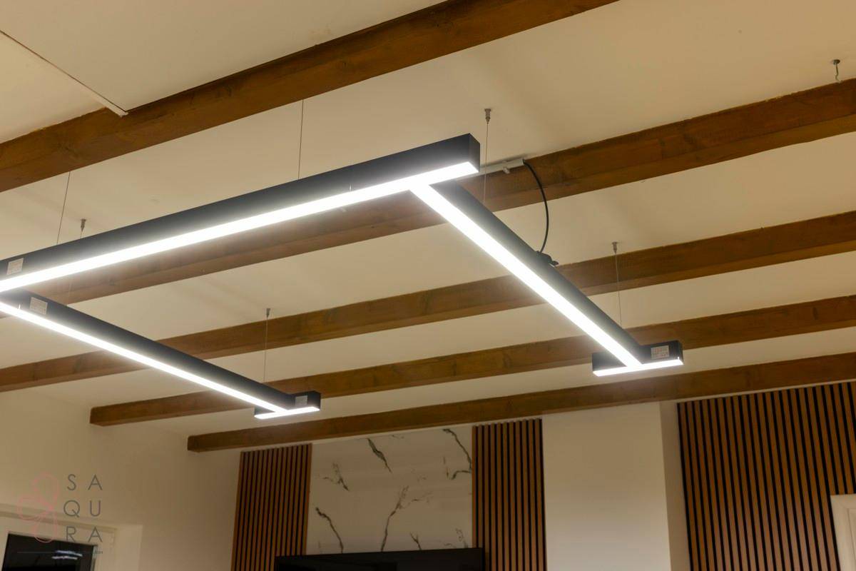 Moderne Deckenbeleuchtung mit LED-Streifen und sichtbaren Holzbalken in einem Wohnraum.