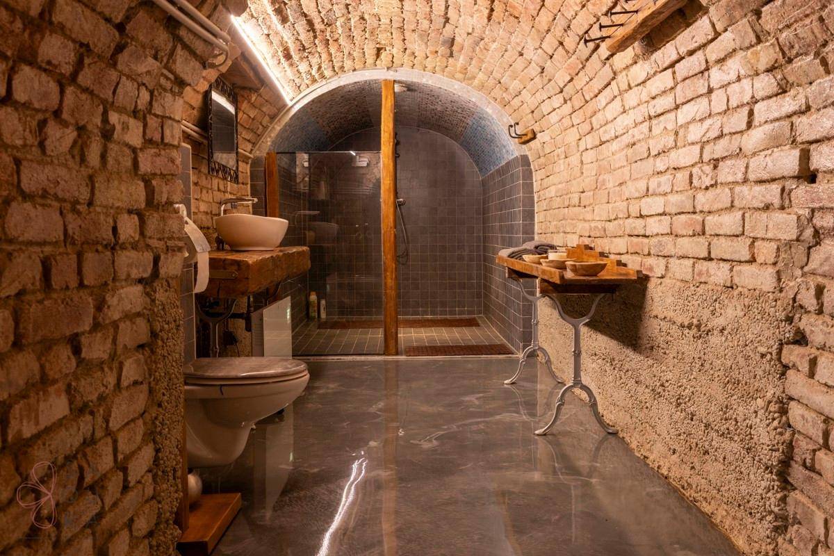 Ein rustikales Badezimmer mit Ziegelwänden, begehbarer Dusche und modernem Waschbecken.